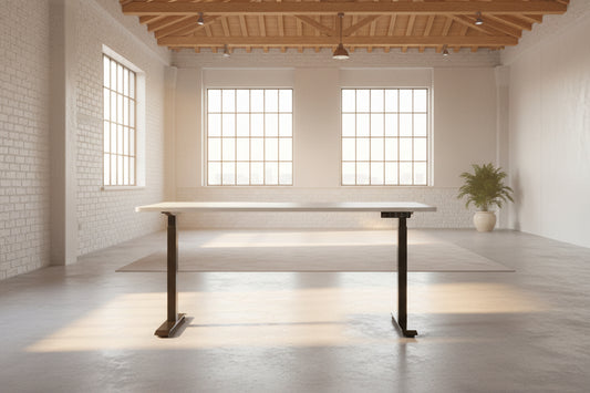 A height adjustable sit stand desk with a white rectangular desktop and black metal frame, shown against an AI background as a tidy warehouse setting